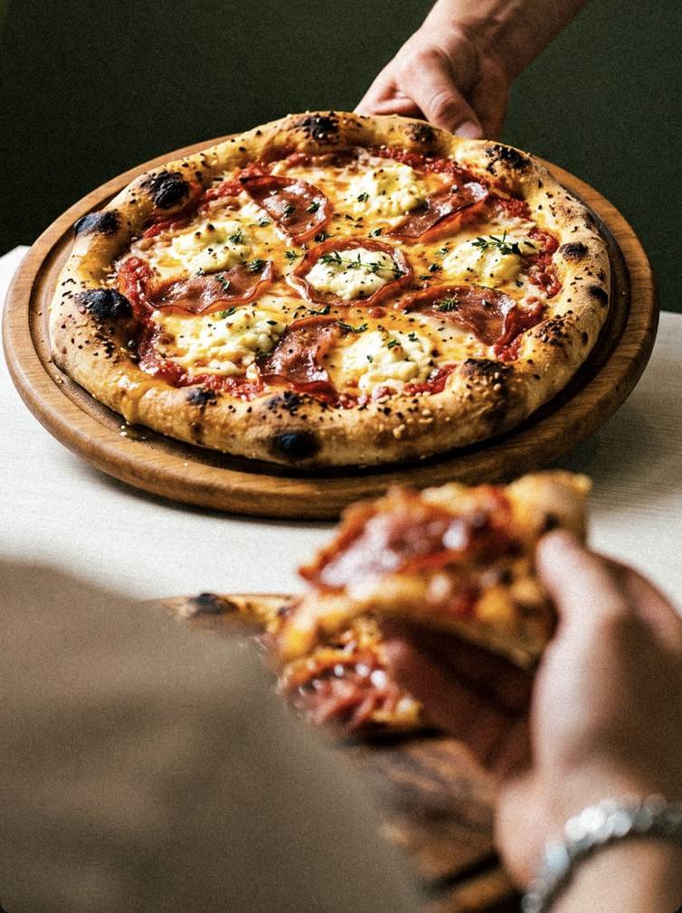 Pizza au pepperoni et à la ricotta sur planche en bois